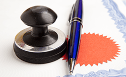 Notary stamp and pen resting on a document with a red embossed seal.